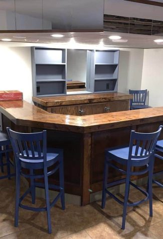 Bar gathering area with six blue bar chairs pulled up to the bar, and one extra in the corner