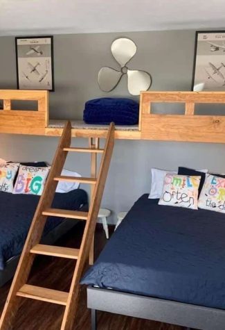 Two double beds with lofted sleeping space above them in an aviation themed room