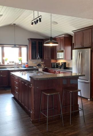 View of the kitchen on the property with its white shiplap ceiling, its many dark cabinets and long island